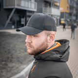 Miehellä on M-Tac Mesh Flex Ripstop Baseball Cap mesh-paneeleilla jalkakäytävällä, ulkoilupäähine säädettävällä Velcro-nauhalla.