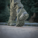 Mies käyttää Tactical Sneakers Demi-Season -kenkiä – kevyt ja mukava luonnossa, näyttää kengän tukevan pohjan ja materiaalit.