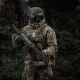 Sotilas maastokuvioidussa varustuksessa kiväärin kanssa kantaa M-Tac Patch M67 Kranaattia 3D PVC taktillisessa liivissä